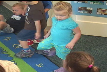 Children march and dance on the rug at group time