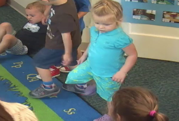 A group of children dance and move during a whole group time activity.