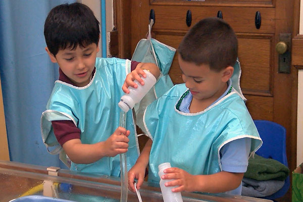 Two children pour liquid into tubes from bottles