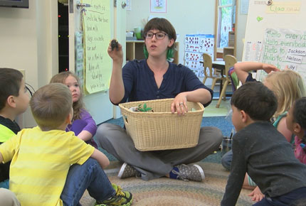 A teacher holding up a toy for children to see during group time