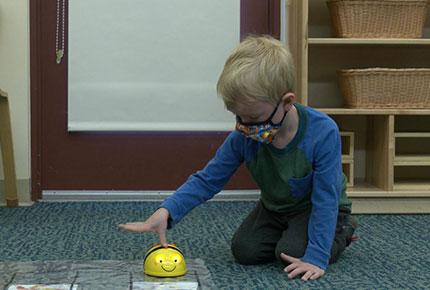 Child pushes button on robotic toy