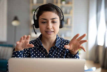 Adult with headphones talking at laptop screen