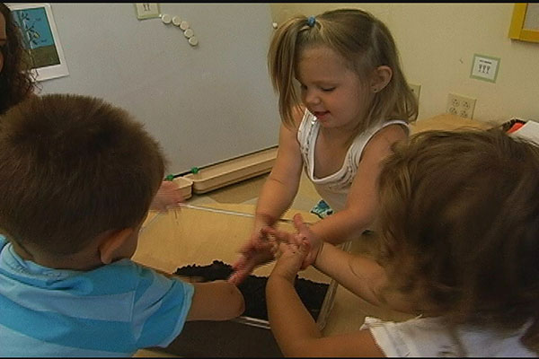 Toddlers play with dirt in a container