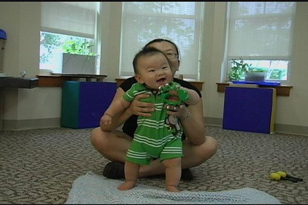 A mom holds her baby in a standing position