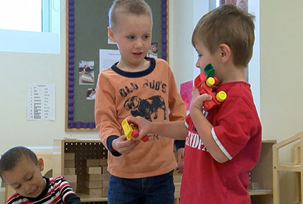 A preschooler offers another child a toy