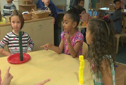 Children play a game comparing stacks of cubes. 