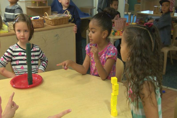 Children compare two stacks of colorful cubes.