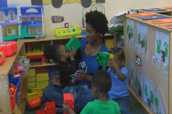 Children build with large blocks with their teacher.