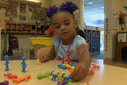 Young girl playing with the plastic replica family.