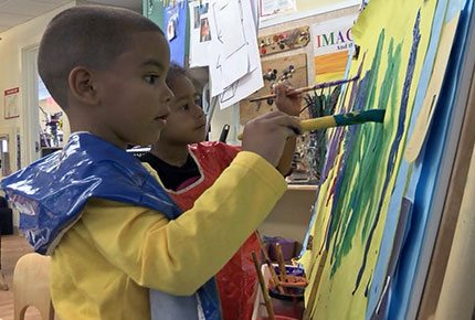 Children painting at an easel.