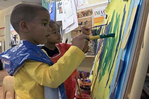 Children painting at an easel.