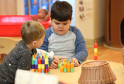 Two children play with a toy at a table.