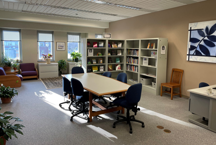 The CTLA Common Space: A conference table with 6 chairs, bookshelves, comfortable seating, green plants, and natural light