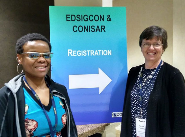 Professors standing in front of "EDSIGCON & CONISAR Registration" sign