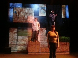 student actor standing in the foreground while other student actors stand on elevated platforms behind them