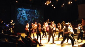 student actors doing a choreographed dance on stage