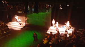 student actors on stage with a large green area between them