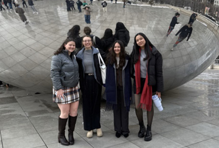 Students posing for photo in front of a large metal ball