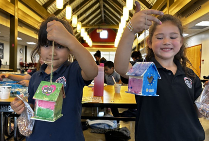 two children holding up painted bird houses