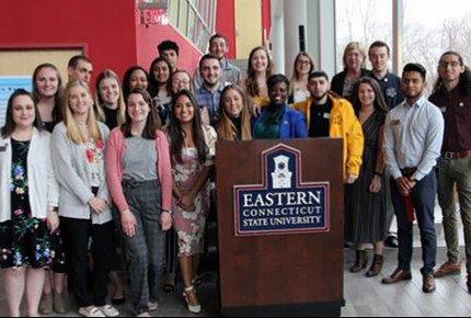 Students posing for photo in front of podium