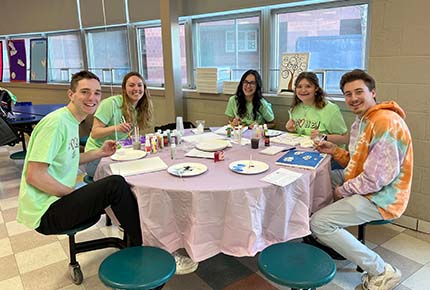 Students sitting around a table painting