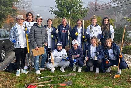 student volunteers posing with various outdoor tools