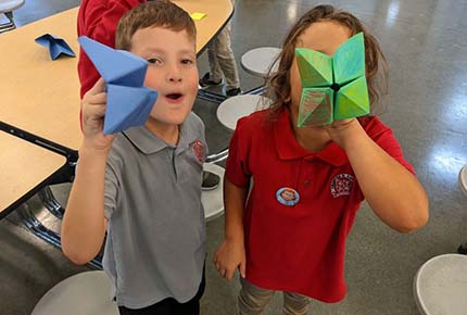 children holding origami projects