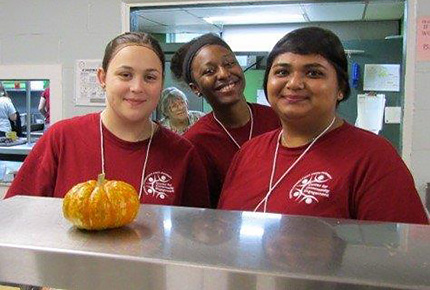 Students posing in front of small pumpkin/gourd
