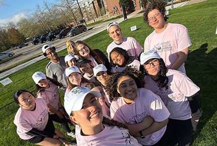 members of the CCE taking a selfie on the lawn outside of the library wearing pink Town Pride Town Wide t-shirts