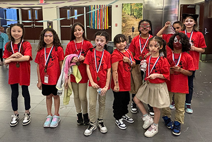 group of children with their faces painted and with temporary tattoos wearing medals and red Windham Public School t-shirts