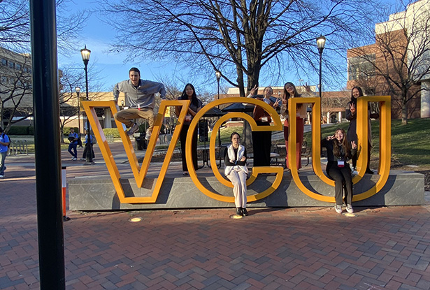 students sitting in a large installation of letters VCU