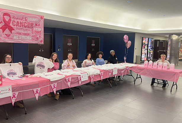 students holding up t-shirts for a breast cancer awareness display