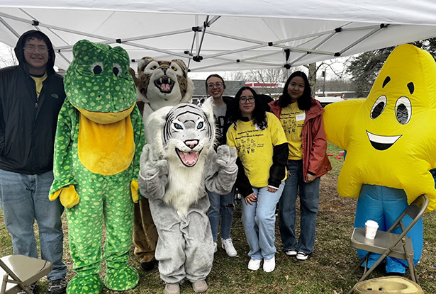 students posing for a photo with people in various mascot outfits