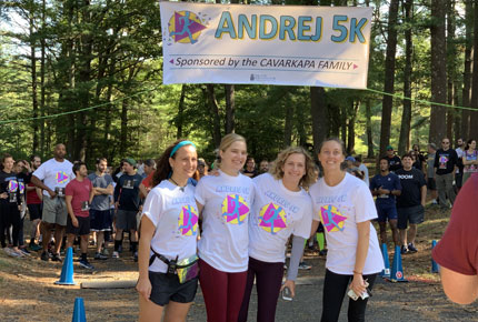 four participants posing for photo in front of Andrej 5K banner