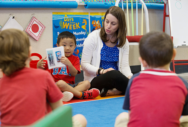 student teacher seated on the floor with preschool children engaged in circle time reading