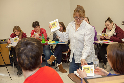 professor handing out books to studentss