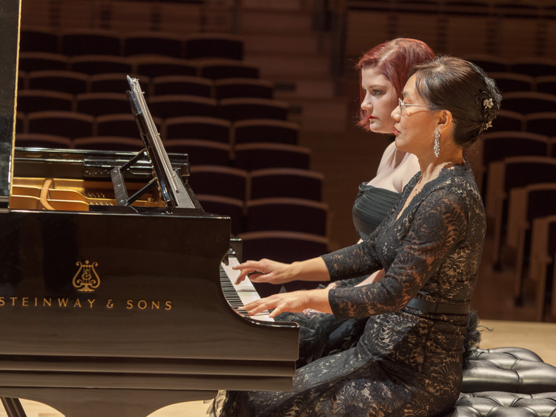 Okon Hwang playing piano with a student