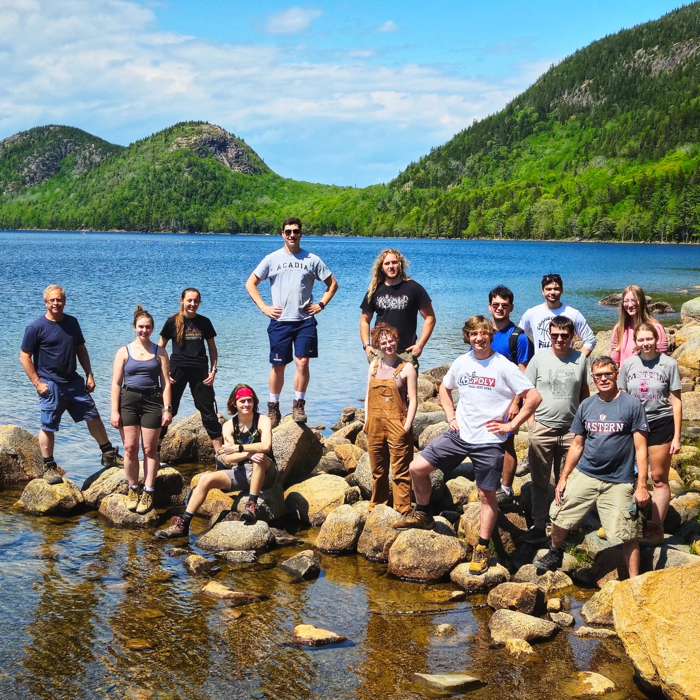 students and professor posing for a photo next to the water in new england