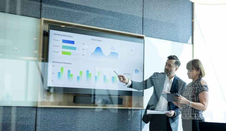 data scientist presenting data on a screen in an office.