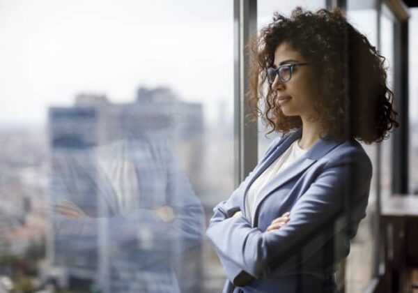 Woman manager looks through a glass window while standing in her office.