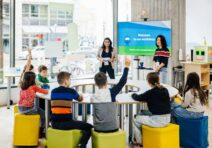 Children raise their hands to ask questions in a classroom.