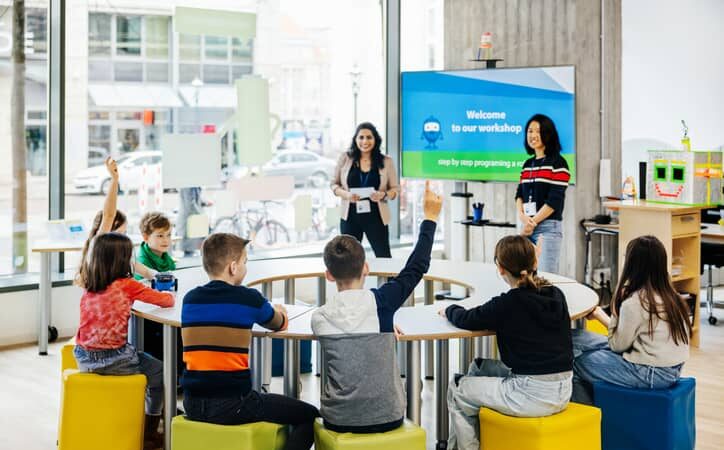 Children raise their hands to ask questions in a classroom.