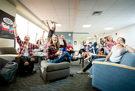 students cheering and watching sports on tv