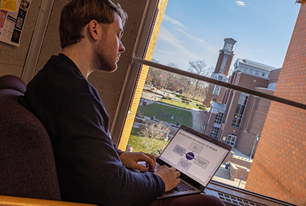 student using a laptop with the clocktower in the background