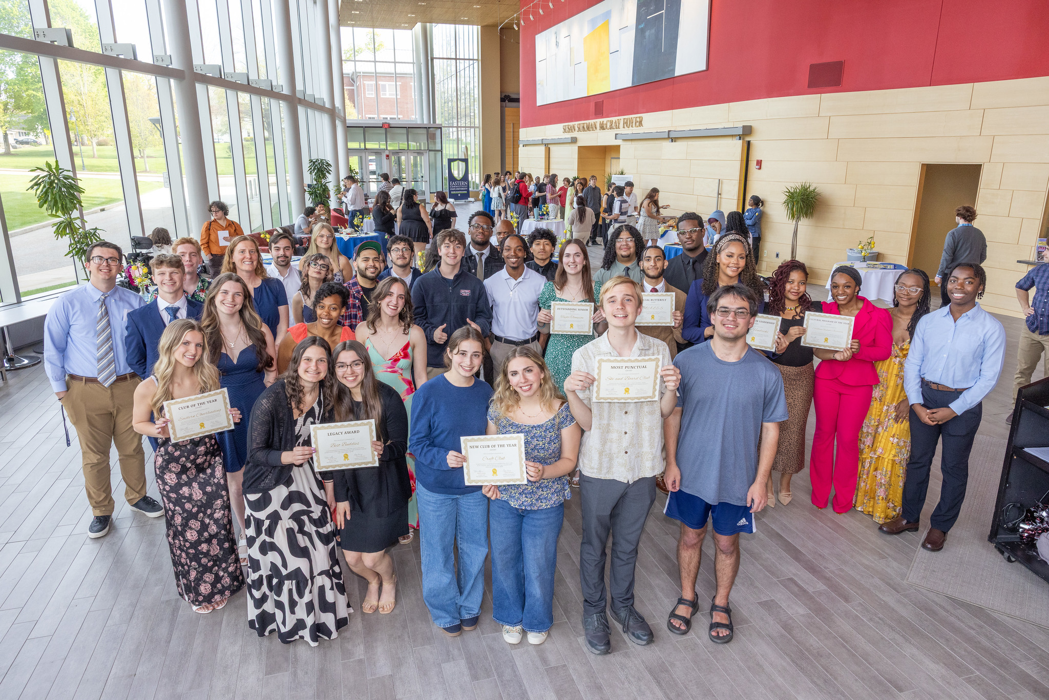 Student club members holding awards in the Fine Arts Instructional Center foyer