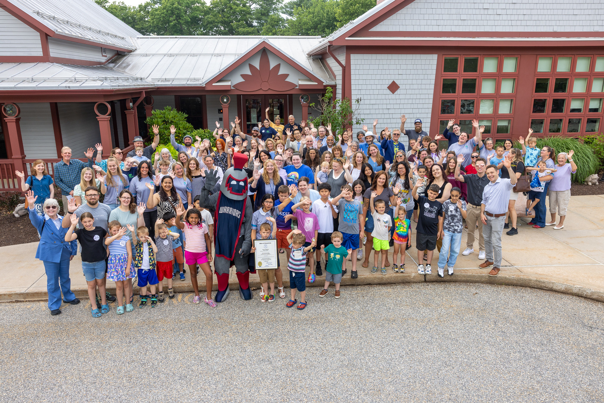 Families, staff, and the Warriors mascot waving outside the Child and Family Development Resource Center