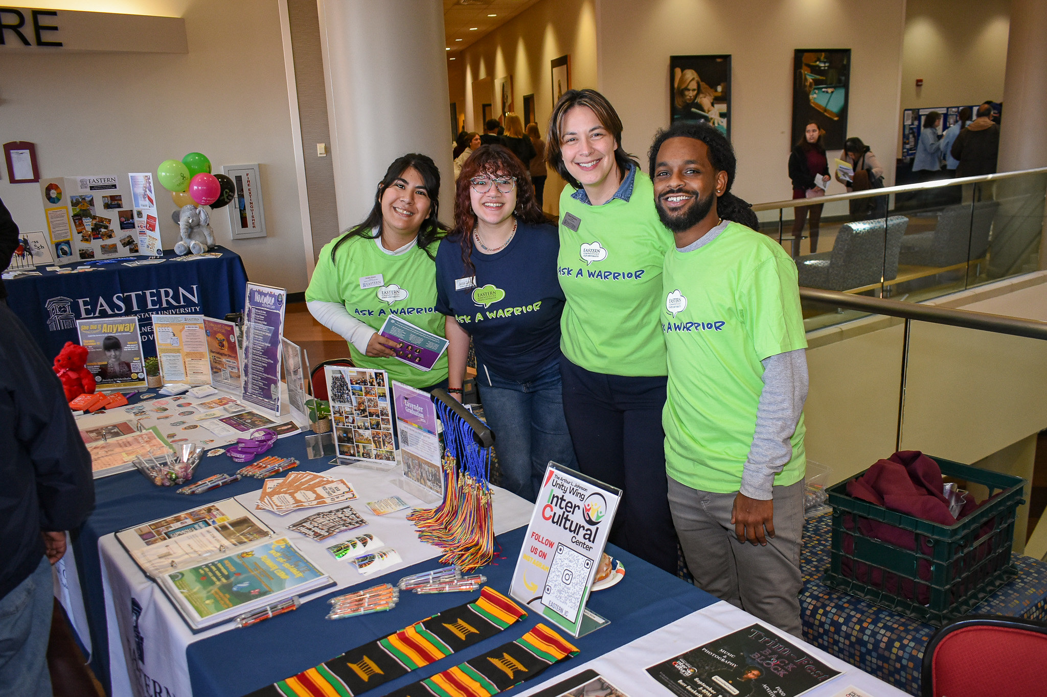 Staff and students in 'Ask a Warrior' shirts at a campus resource table