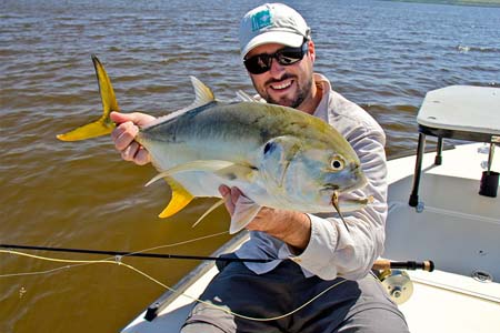 Alumni Kierran Broatch holding up a fish he caught