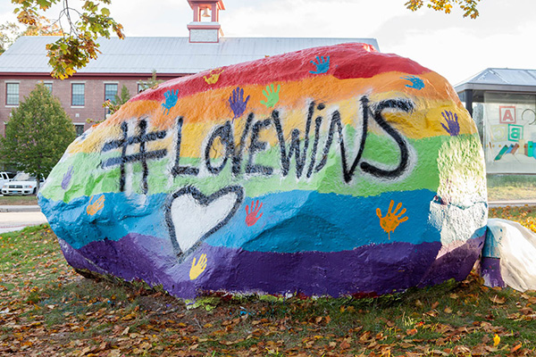 a large rock painted with a rainbow and #lovewins