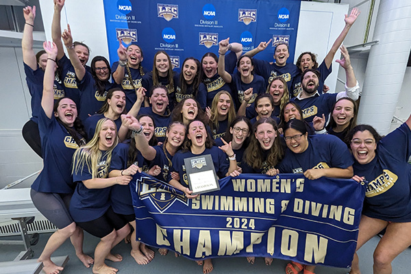 Eastern's Women's Swimming and Diving team (2024) posing with their champion banner and plaque